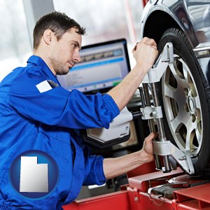 a mechanic adjusting a wheel alignment machine clamp - with Utah icon