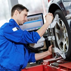 a mechanic adjusting a wheel alignment machine clamp